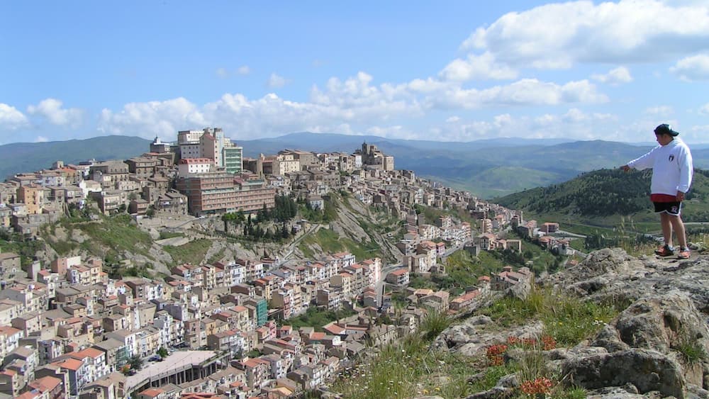 Une ville de montagne, avec des bâtiments historiques et une personne se tenant debout sur un promontoire rocheux.