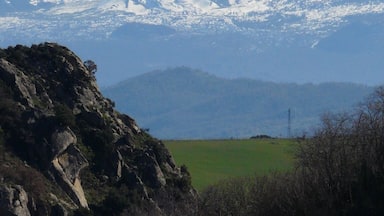 A snow-covered mountain with a rocky foreground and a green valley.