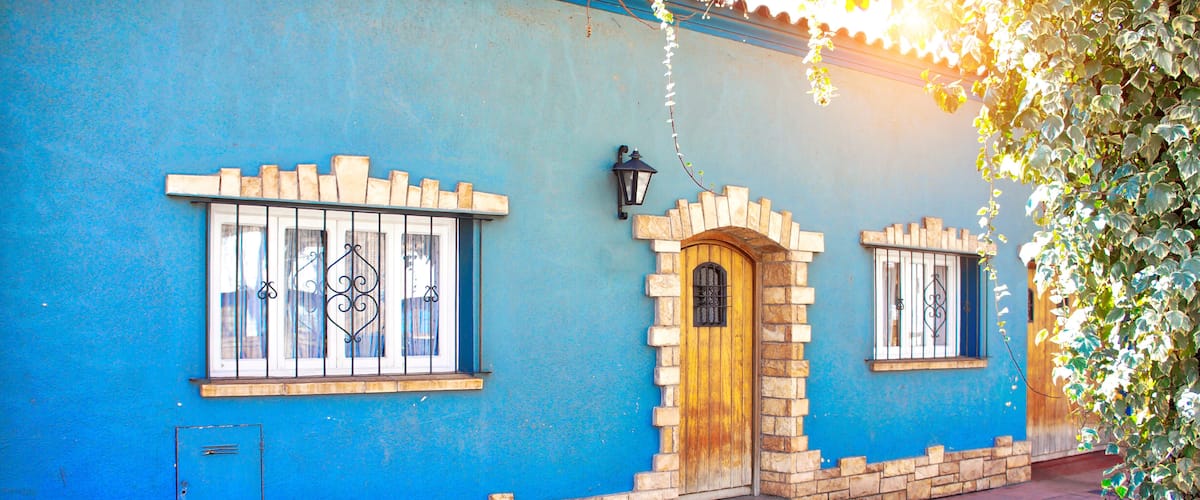 A blue building with a wooden door and windows with metal bars.
