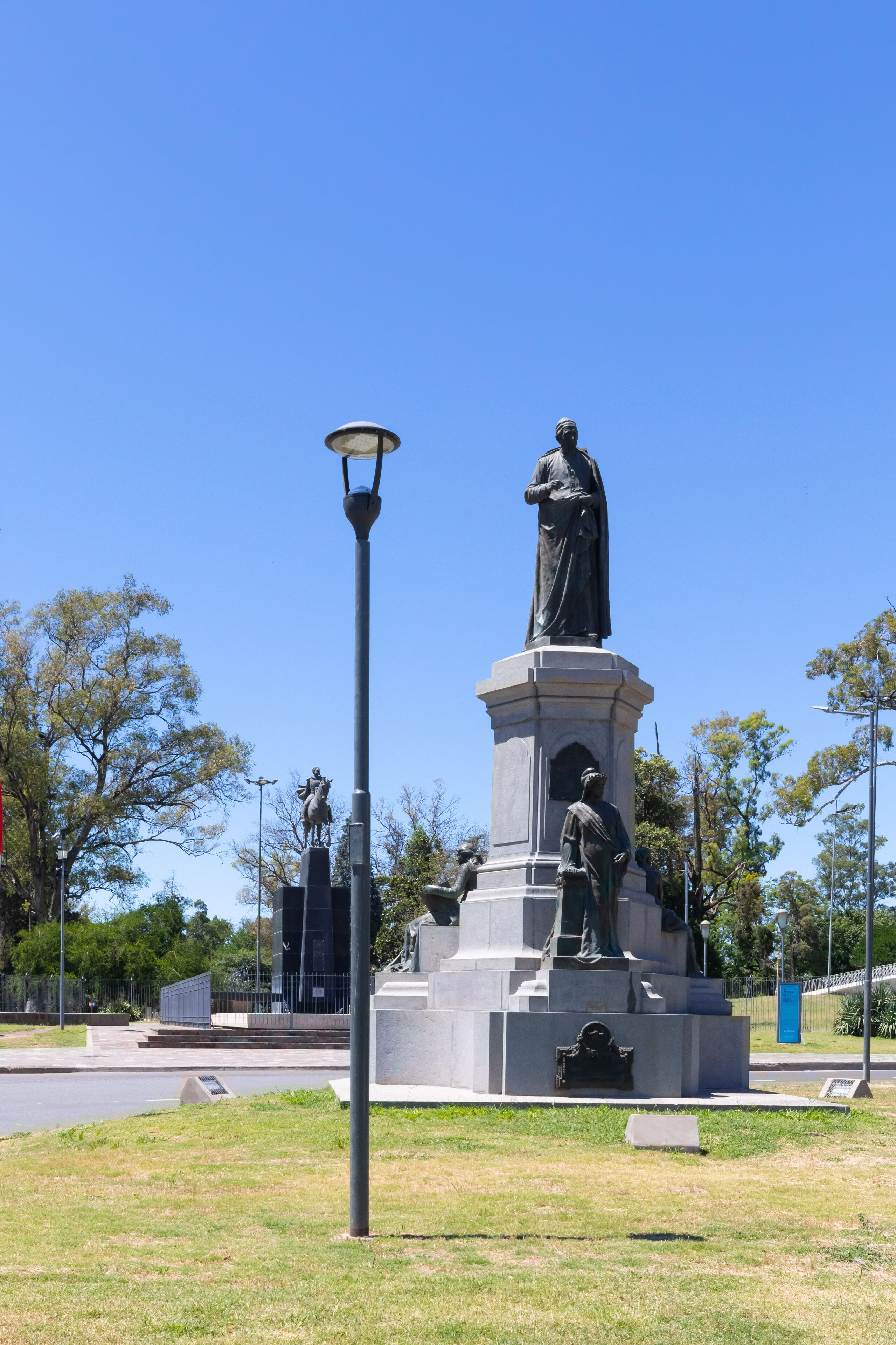 A statue of a man on a pedestal with a lamp post nearby.