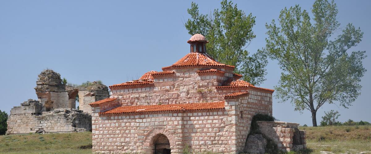 A historic stone building with a red-tiled roof and arched entrance.