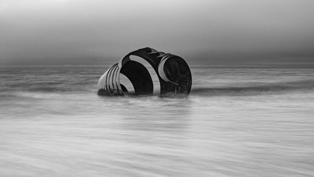 A large, cylindrical structure with a curved top, partially submerged in calm ocean waters.