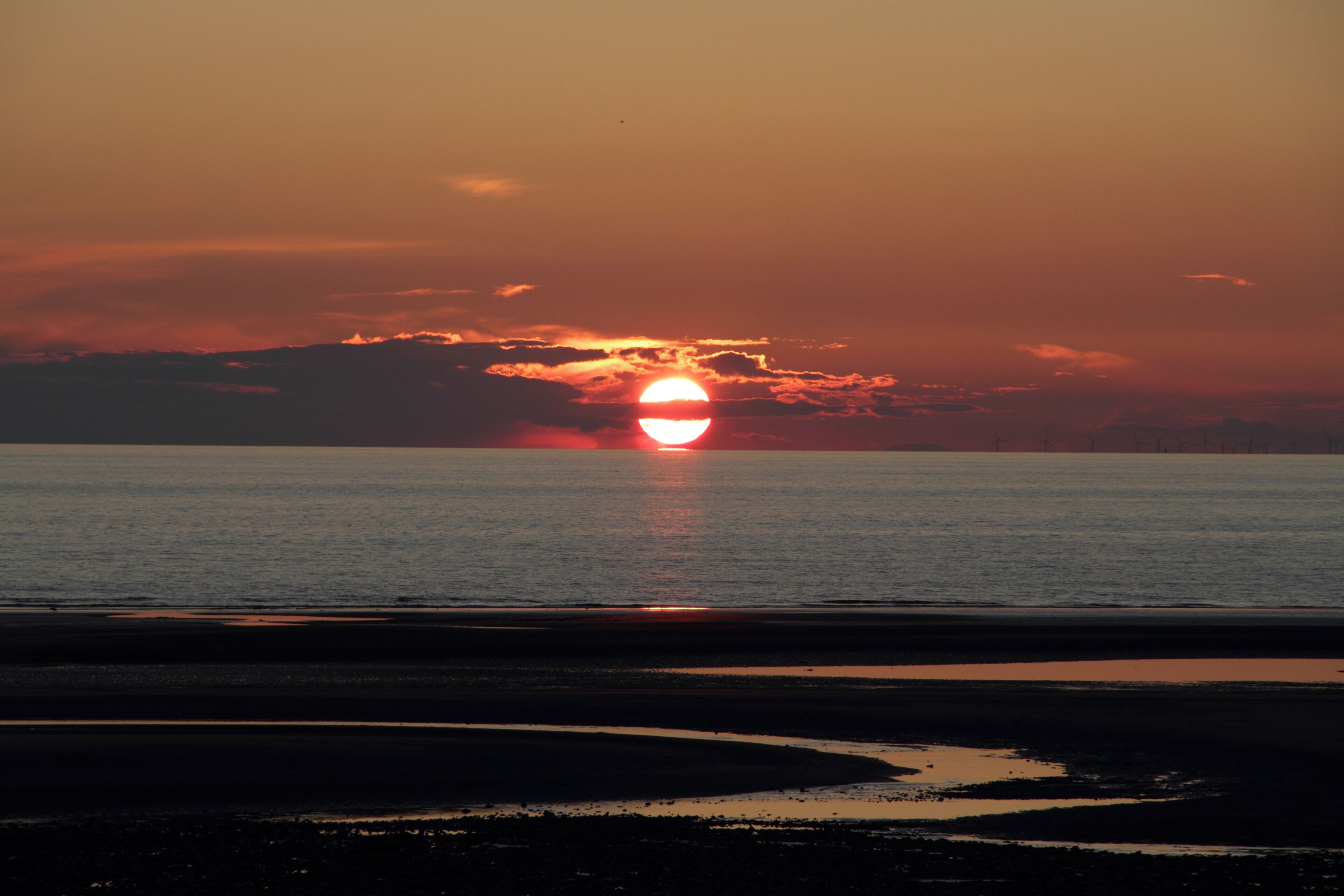 A sunset over a calm sea with a visible horizon line.