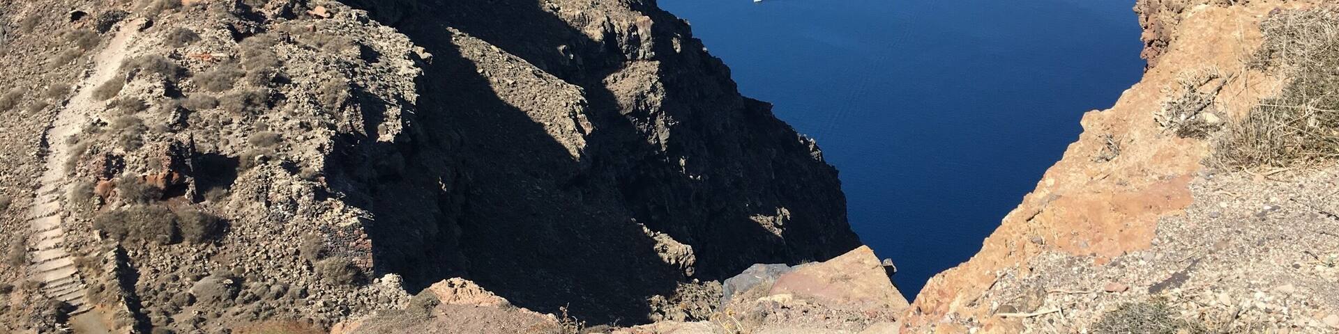 A rugged coastline with a steep cliff and a narrow path leading down.