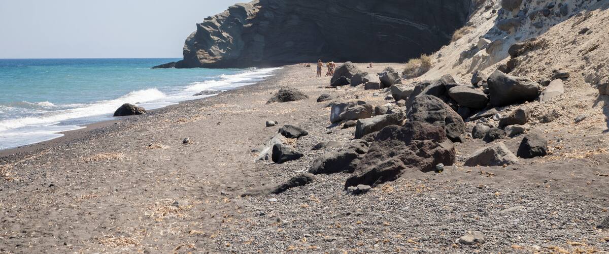 A rocky beach with large boulders and a steep cliff.