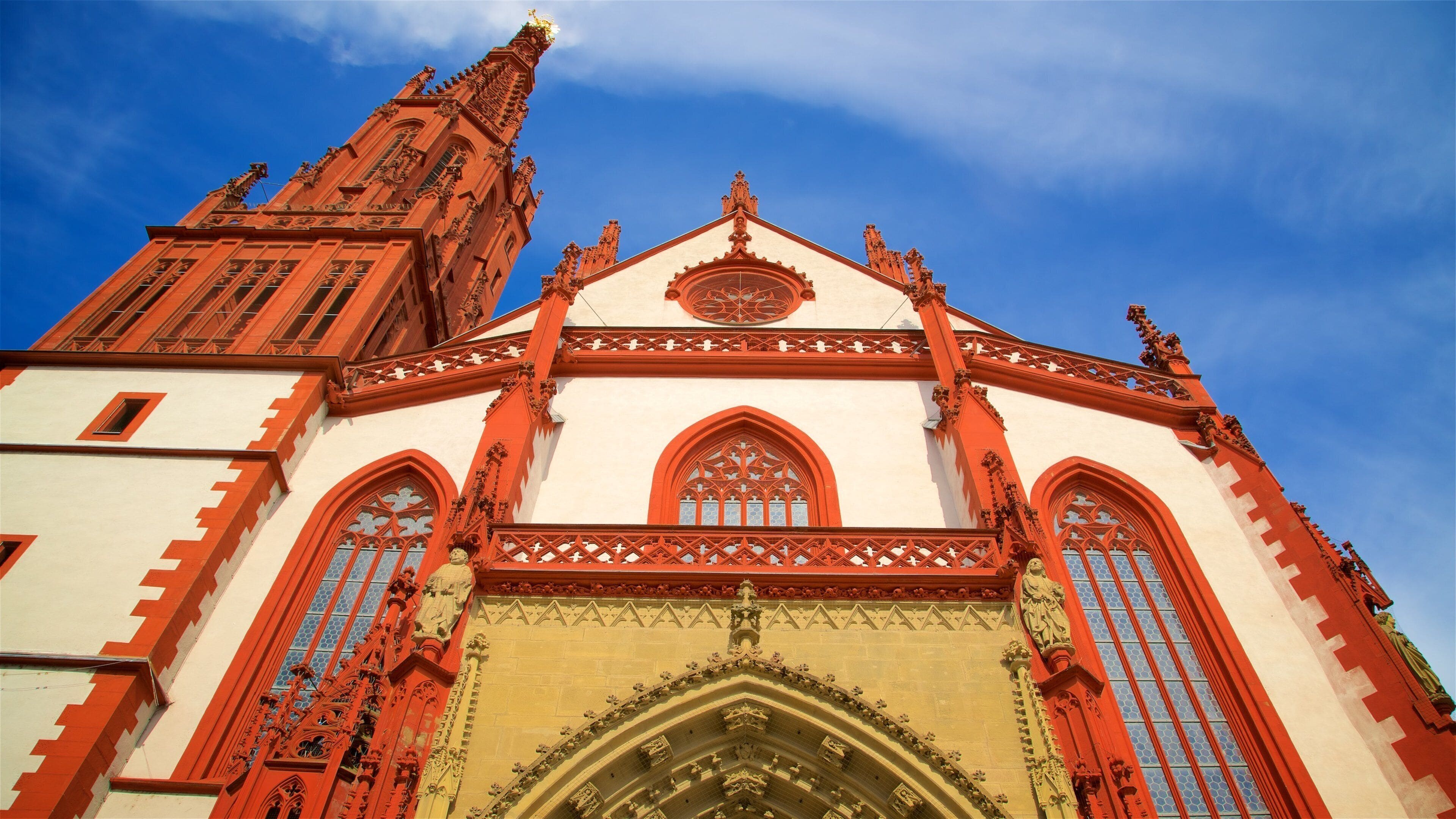 A Gothic-style church with red and white architecture, large arched windows, and a prominent tower.