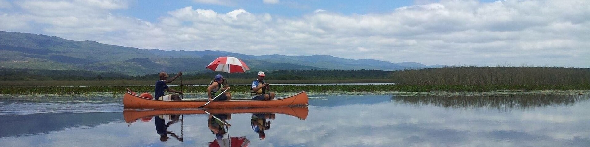 A calm lake with a canoe and an umbrella.