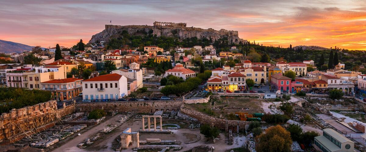 A historic town with colorful buildings, ancient ruins, and a prominent castle on a hill.