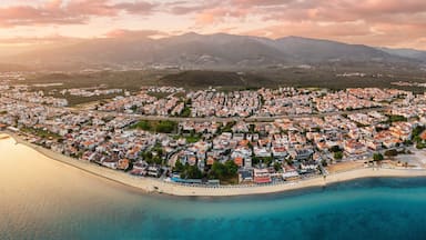 Calm sea reflecting the warm colors of sunset over the coastal town of Akcay, Turkey, with mountains in the background