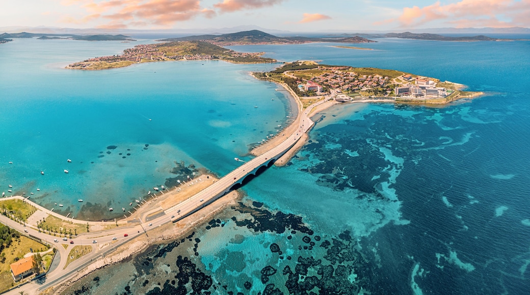 Panoramic aerial view of Cunda Island and Ayvalik, Turkiye, connected by a bridge, showcasing the vibrant turquoise Aegean Sea and coastal town