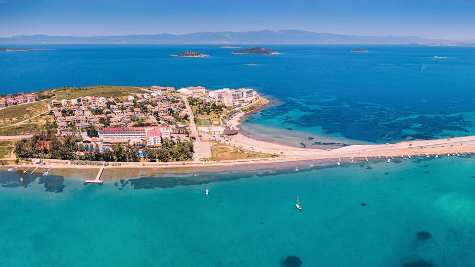 Une vue aérienne d’une ville côtière, avec une baie, un pont et une mer d’un bleu limpide.