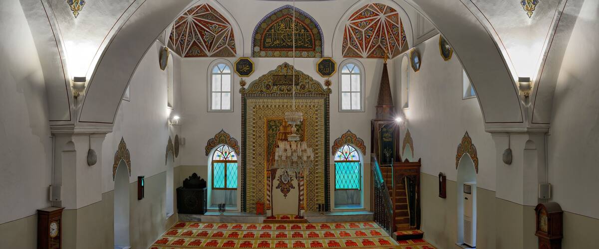 An ornate interior with a large central archway, patterned floor, and decorative ceiling.