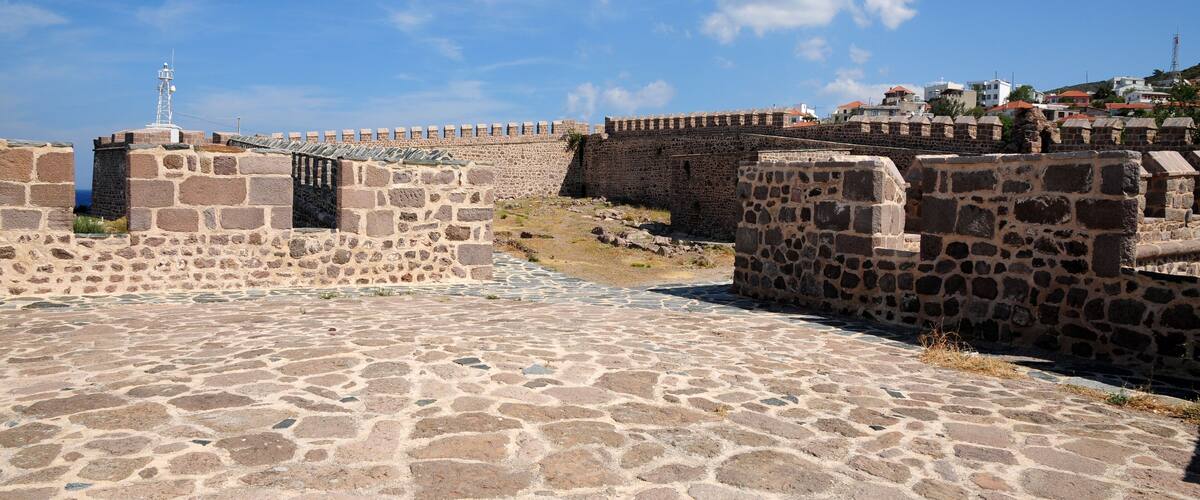 A stone fortification with a watchtower, cobblestone pathways, and a clear blue sky.