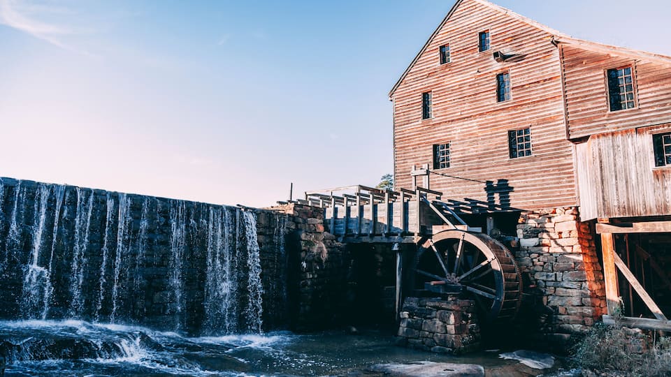 A wooden mill with a water wheel and a waterfall.