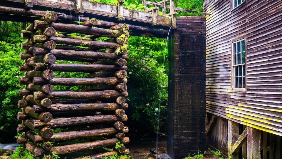 A wooden log structure, a wooden house, and a waterfall.