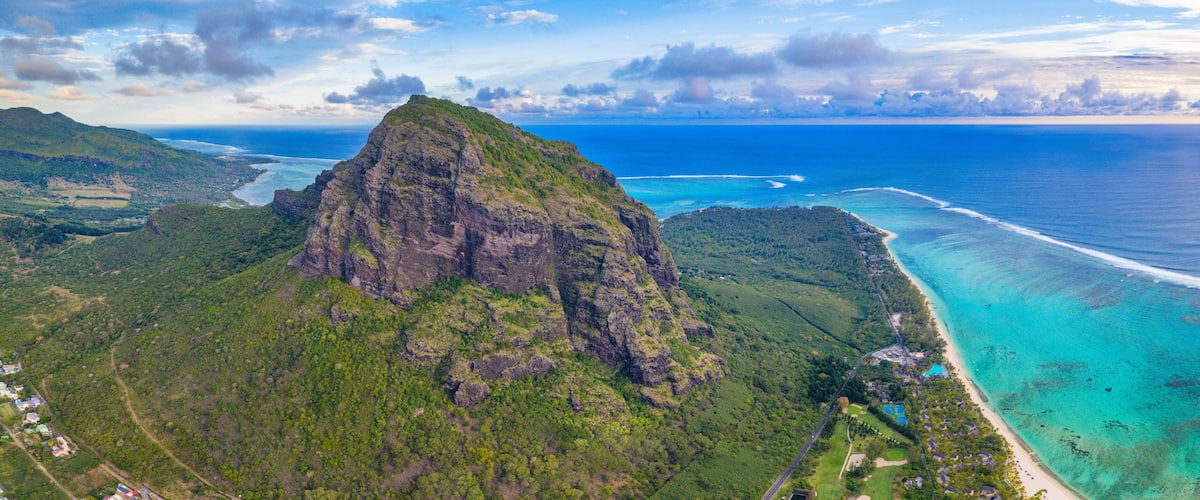 A mountainous landscape with a coastal area featuring clear turquoise waters and a small settlement.