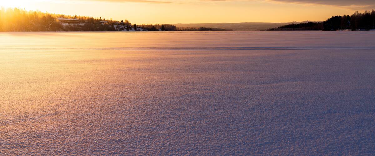 A frozen lake with a sunset in the background.