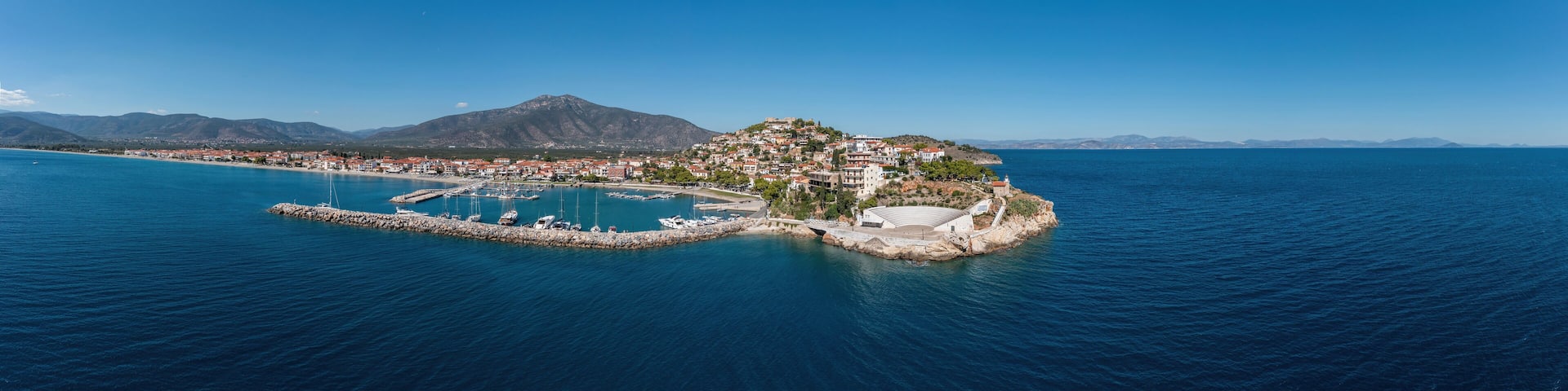 Paralio Astros port, Peloponnese Greece. Aerial drone panoramic view of town, boat, sea, sky. Banner