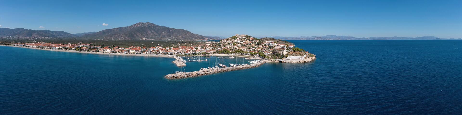 Paralio Astros port, Peloponnese Greece. Aerial drone panoramic view of town, boat, sea, sky. Banner