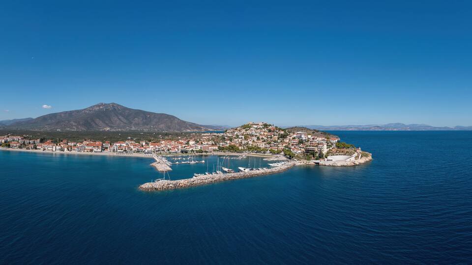 A coastal town with a mountain in the background and a clear blue sky.