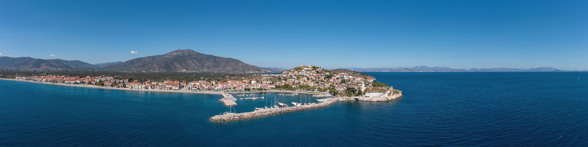 Paralio Astros port, Peloponnese Greece. Aerial drone panoramic view of town, boat, sea, sky. Banner