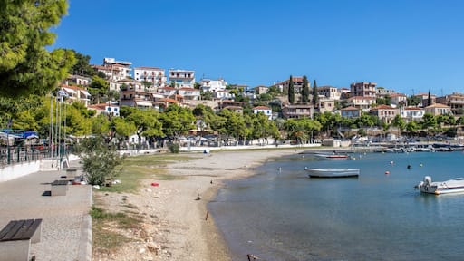 Paralio Astros harbor in Arcadia, Peloponnese, Greece, boats floating upon calm blue water, hillside houses, and clear blue sky