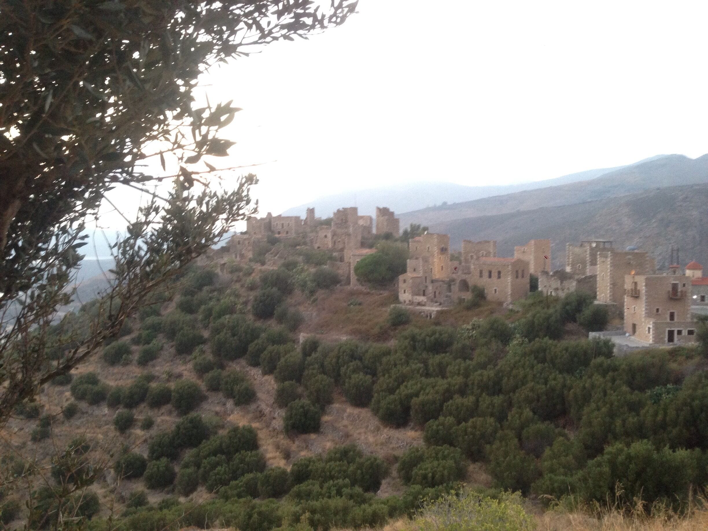 A historic stone fortress on a hill with dense shrubbery.