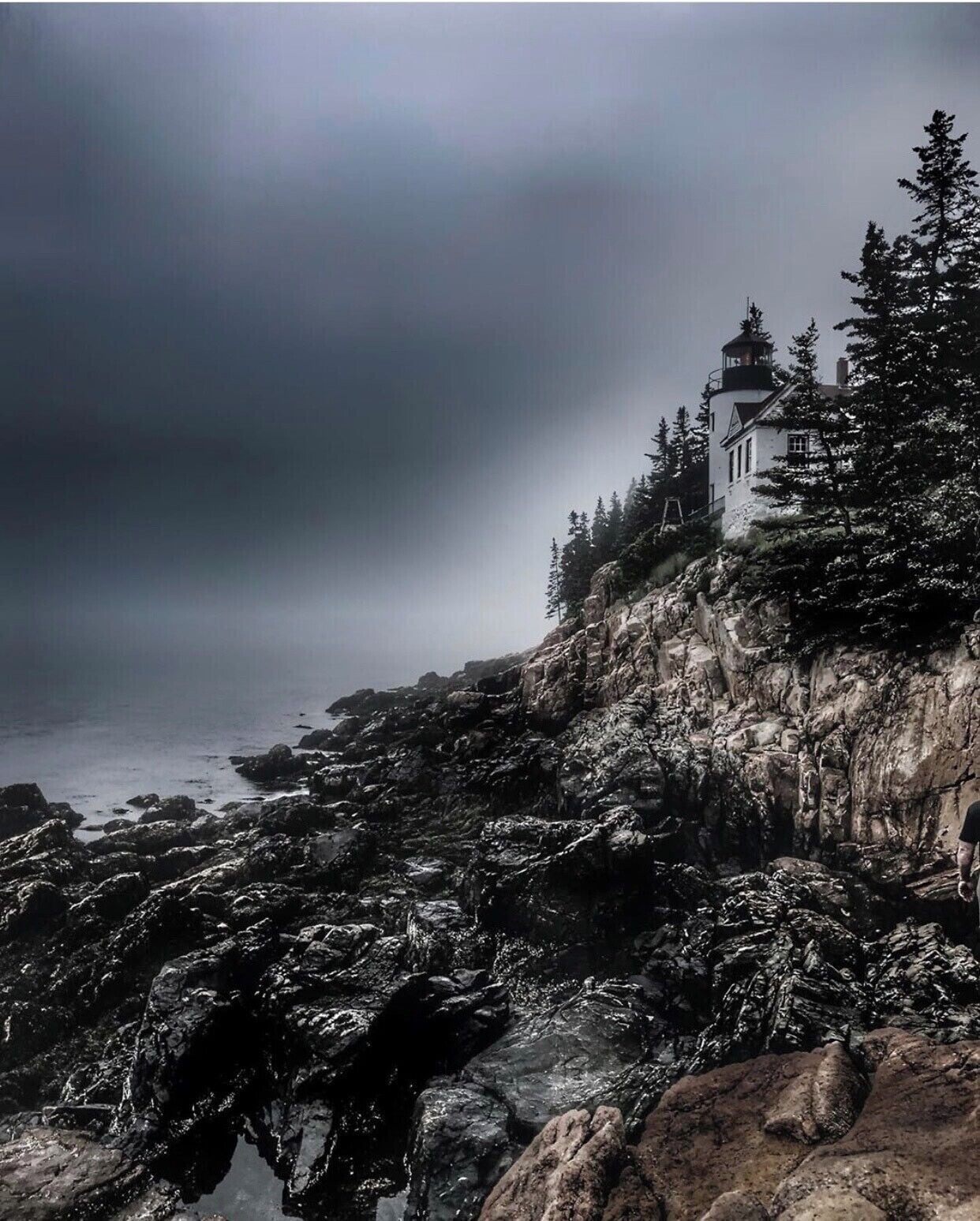 A lighthouse on a rocky cliff overlooking the ocean.