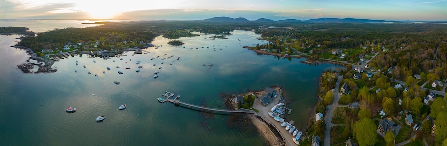 Un pueblo costero con un puerto deportivo, barcos y un puente que lo conecta a una isla.