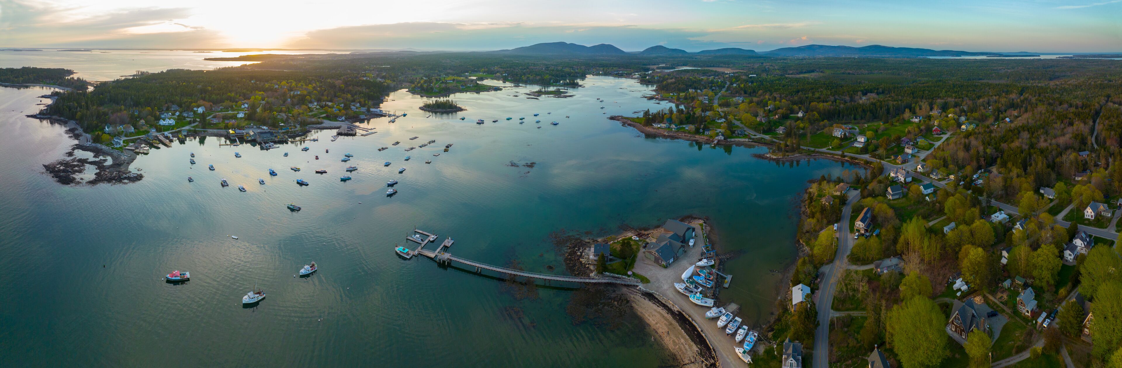 A coastal town with a marina, boats, and a bridge connecting to an island.