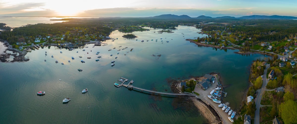 A coastal town with a marina, boats, and a bridge connecting to an island.