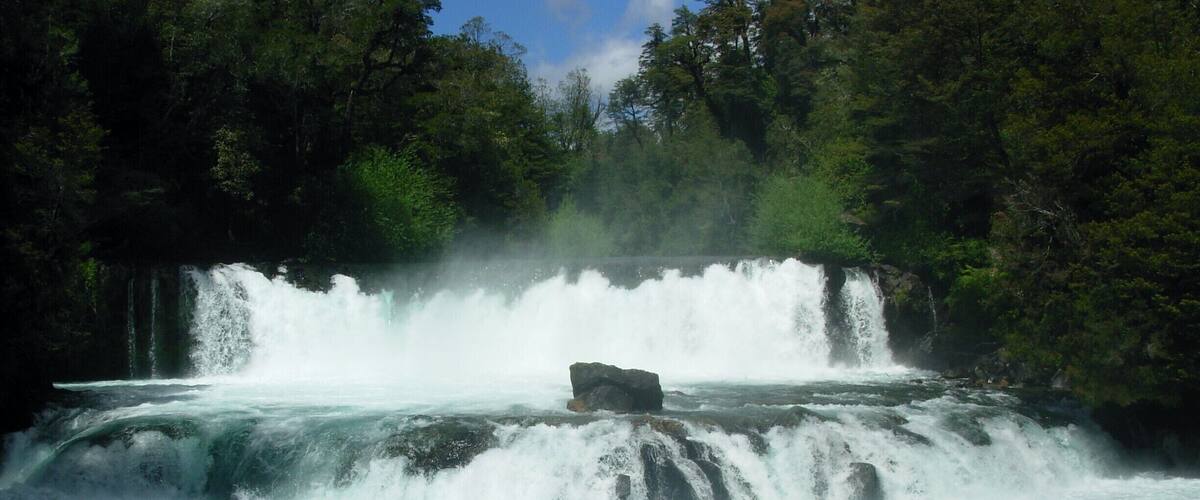 A waterfall cascading over rocks in a forested area.