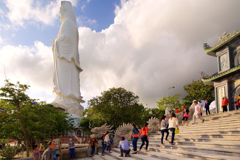 A large white statue, a dragon sculpture, and a traditional archway with inscriptions.