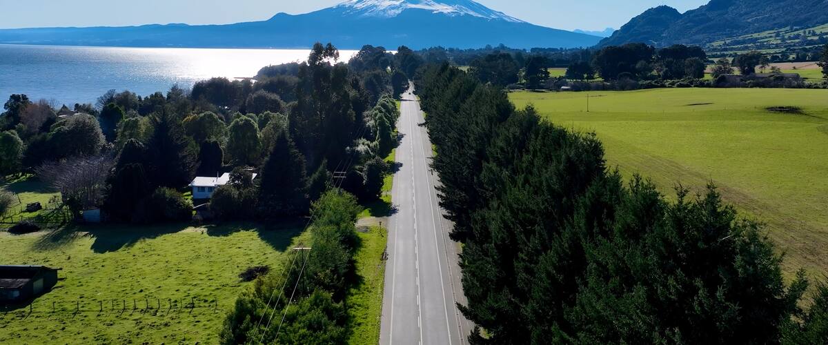 A road leading to a mountain, surrounded by green fields and trees.