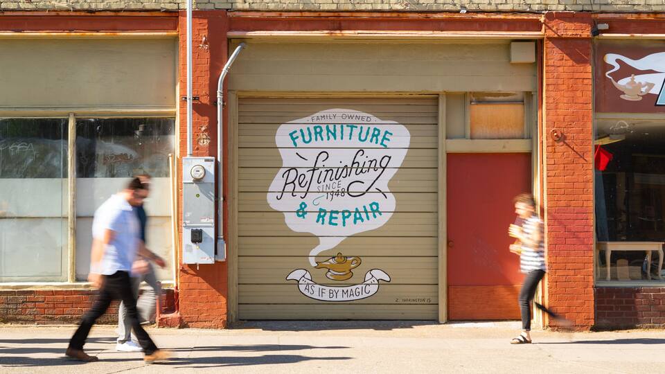 A storefront with a large sign advertising furniture refinishing and repair services.