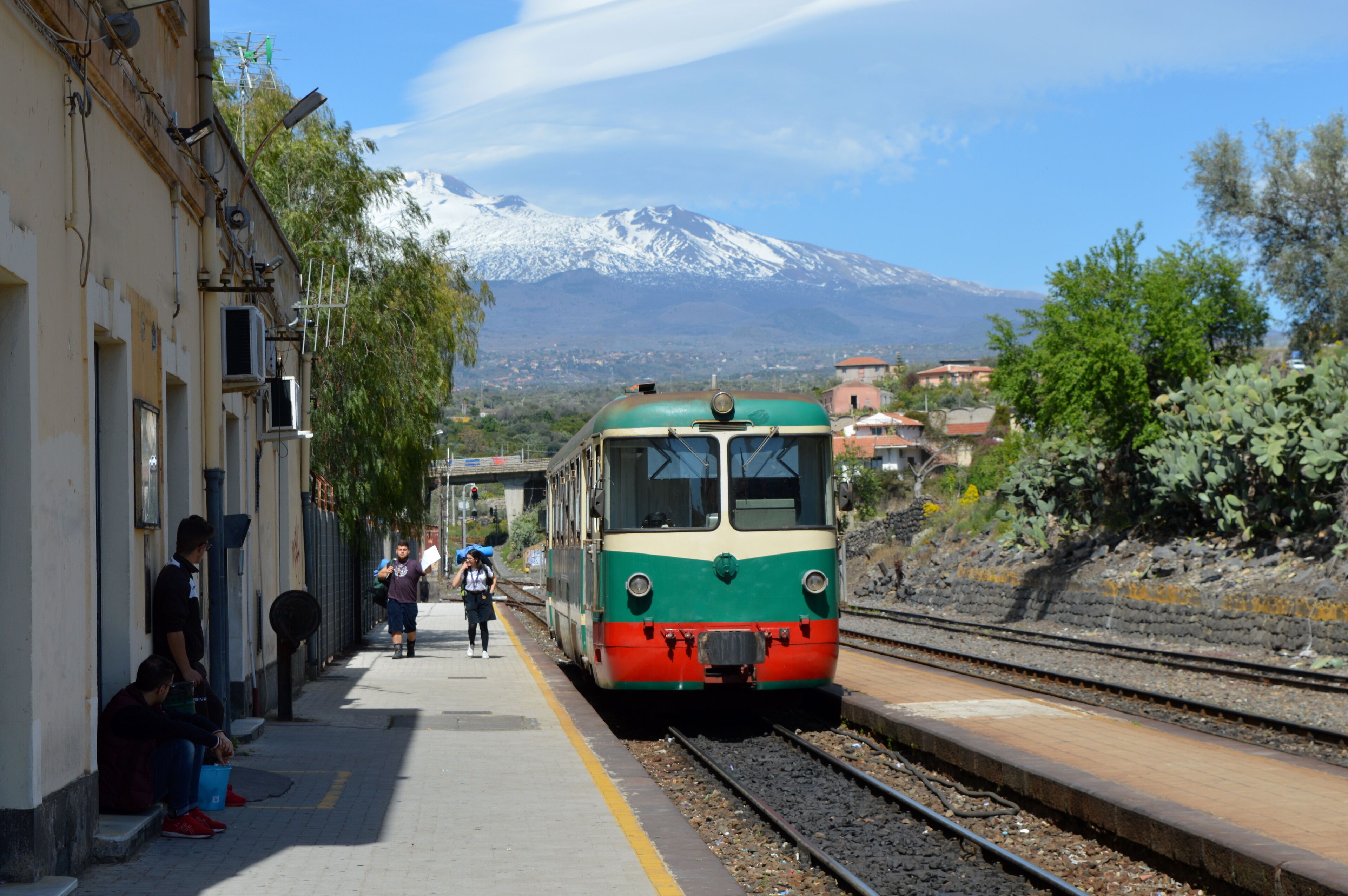 A train at a station with a snow-capped mountain in the background.