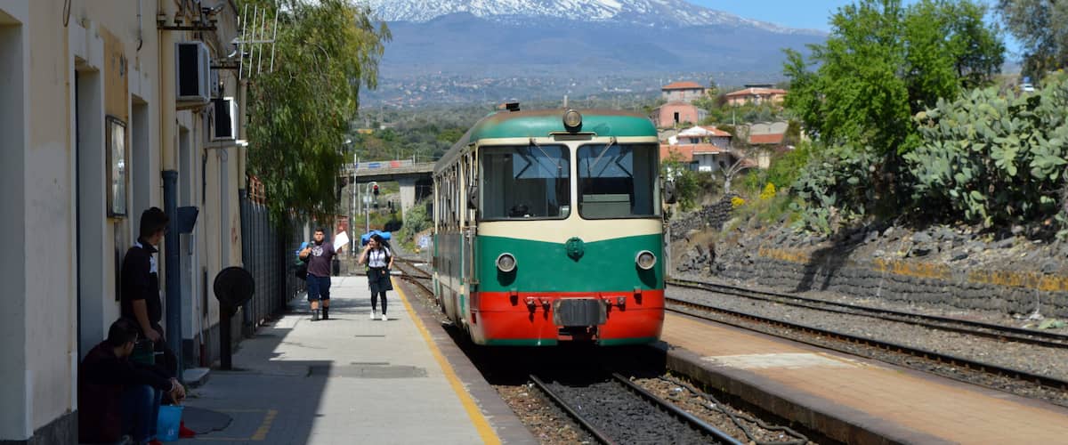 A train at a station with a snow-capped mountain in the background.