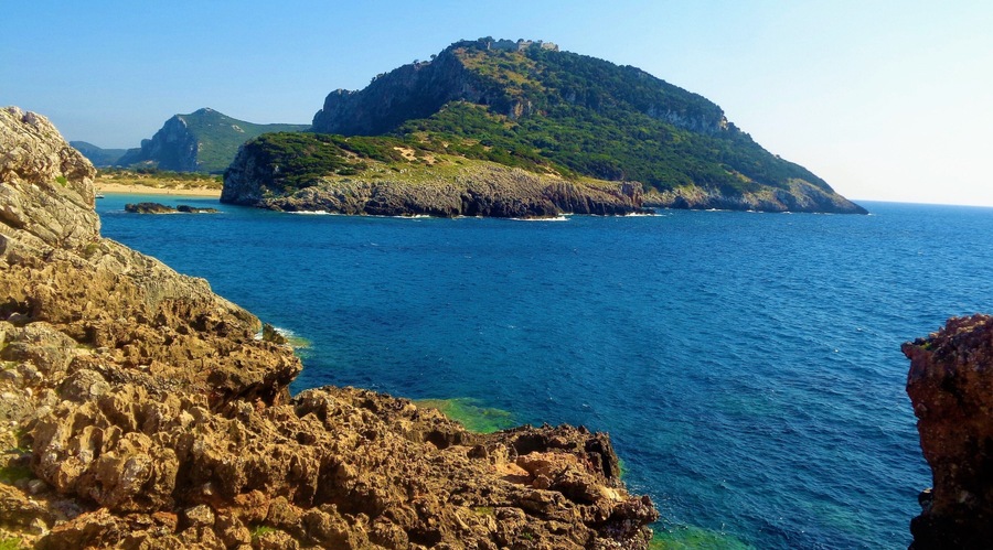 I took this photo in Messinia, Greece in summer 2016. It's of Voidokilia Beach and it's surroundings. Voidokilia Beach is on the Peloponnese peninsula and it was the most picturesque beach that I visited during that Greek trip, which was almost exclusively in Messinia. On that mountain is Nestor's Cave and above this are the ruins of a 13th-century Frankish castle (Old Navarino or Palaiokastro). Look closely and you will see :). I didn't get to walk up there. It was brutally hot that day and I spent most of the time at the beach. But, I did make time for some hiking. Near where I took this photo there was a lot of medieval or ancient ruins. Near those beautiful rocks. I had to be careful when walking on them, but it was worth it!