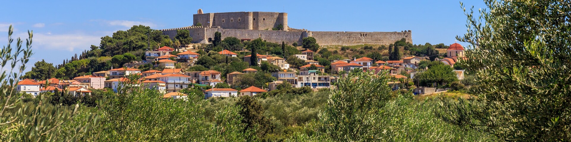 A historic castle atop a hill overlooking a village with red-roofed houses.
