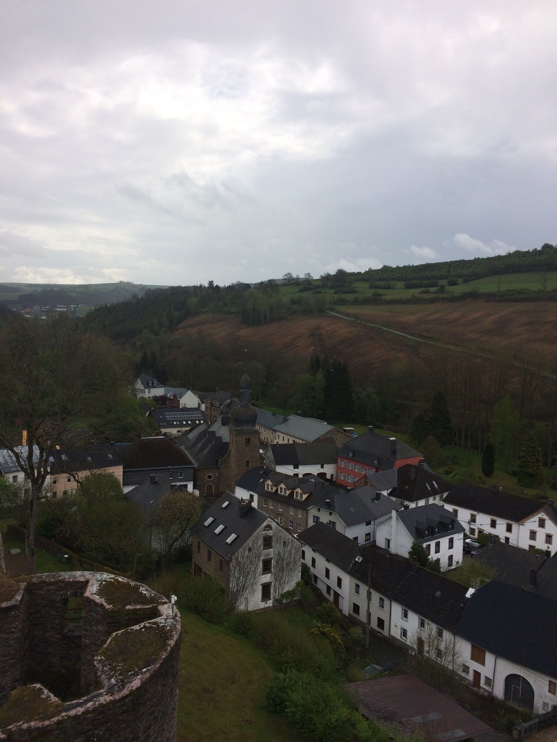 A village with historic buildings, a church, and rolling hills in the background.
