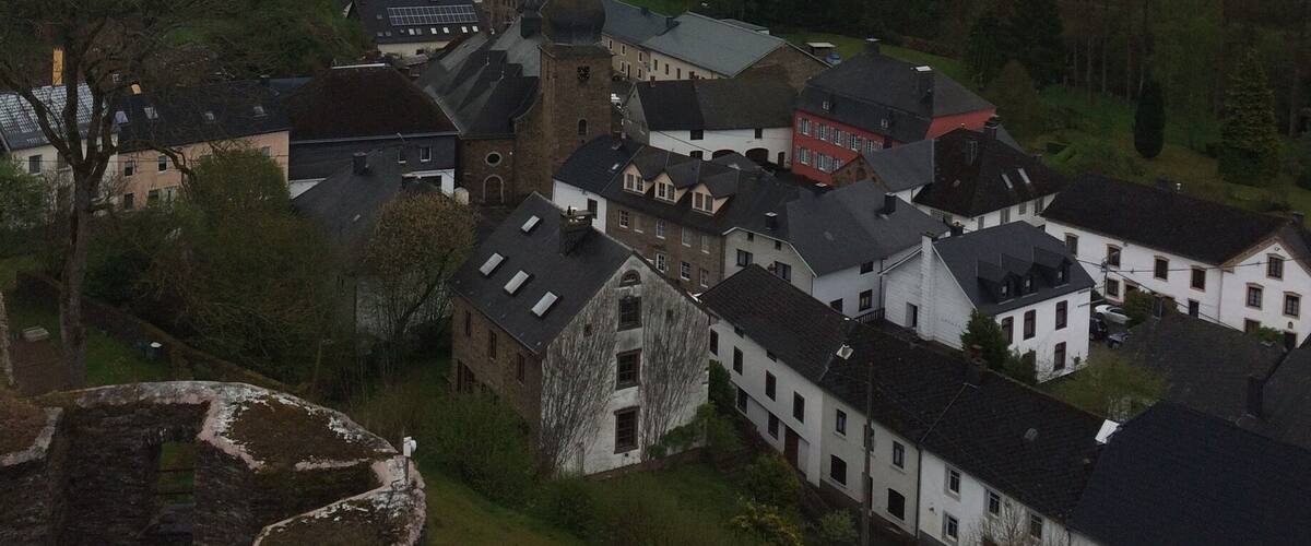 A village with historic buildings, a church, and rolling hills in the background.
