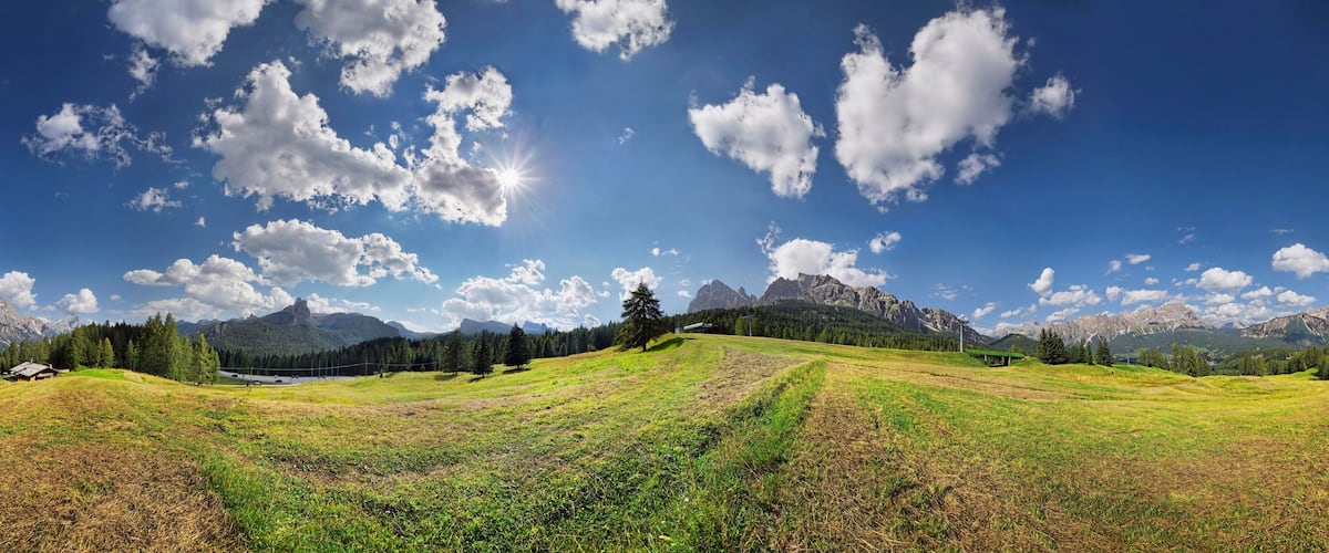 A mountainous landscape with a clear sky, a small house, and a distant castle.
