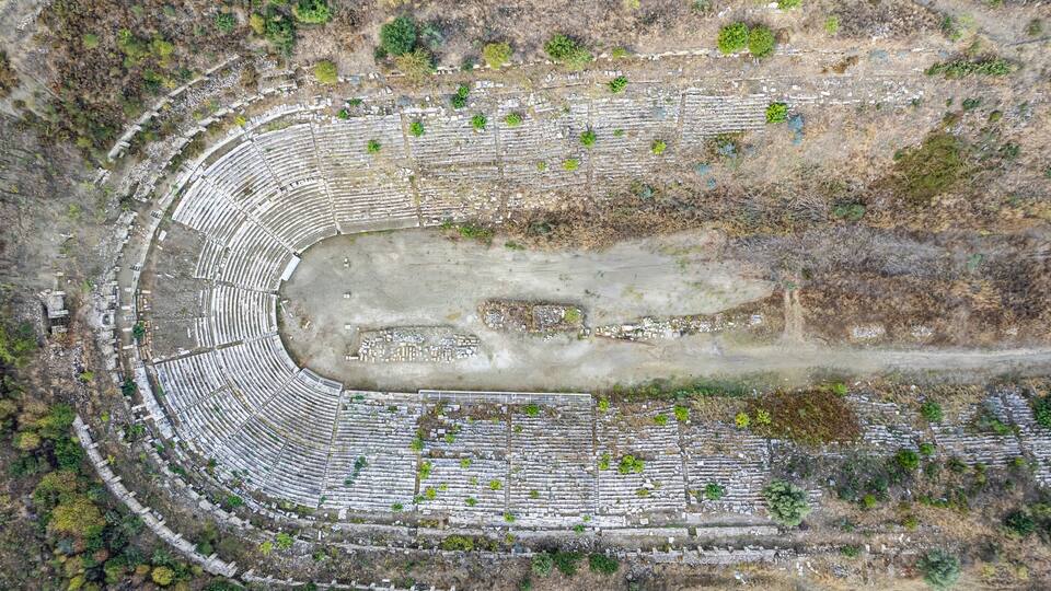 An abandoned amphitheater with a central stage and tiered seating.