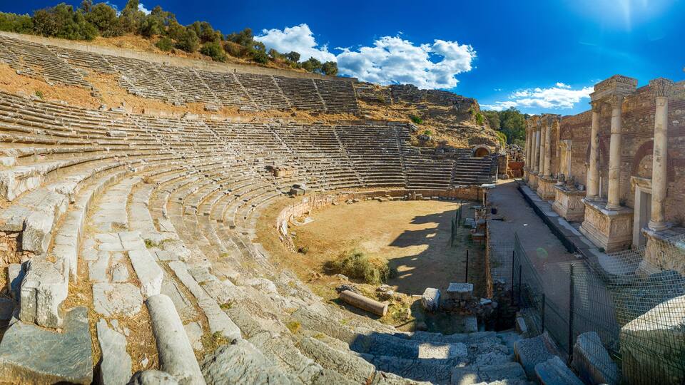 An ancient amphitheater with stone seating and columns.