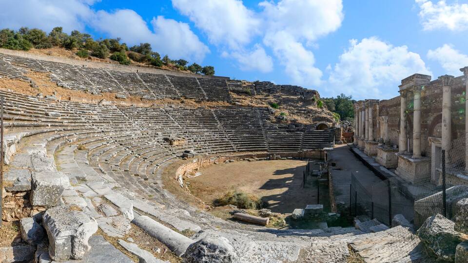 An ancient amphitheater with stone seating and columns.