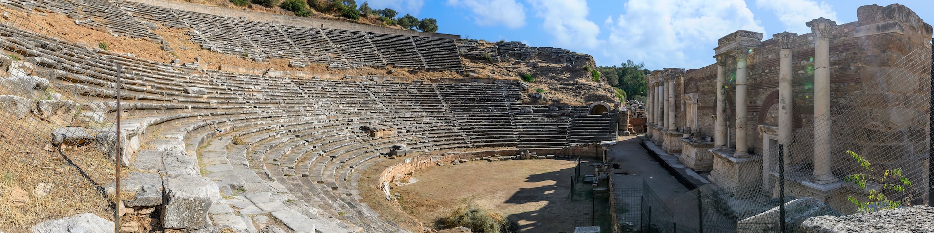 Un antiguo anfiteatro con asientos de piedra y columnas.