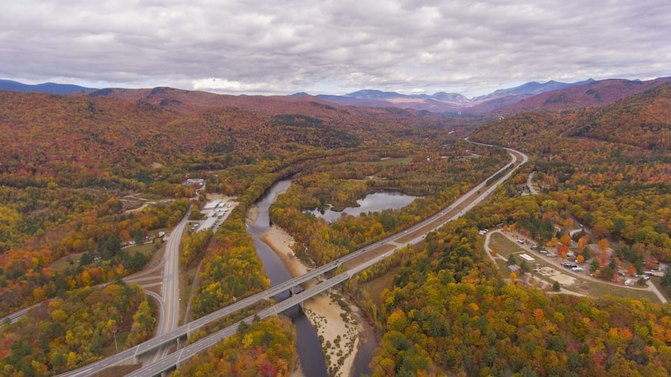 A river flowing through a forested valley with a bridge crossing over it.