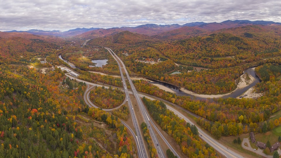A winding highway through a mountainous area with autumn foliage.