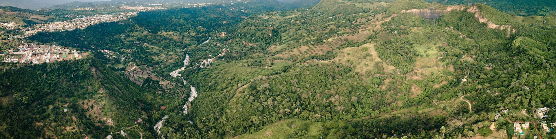An aerial view of a mountainous landscape with a river winding through it, surrounded by dense forests and scattered settlements.