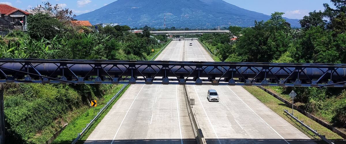 A road leading to a mountain with a clear sky.